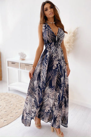 Woman wearing a casual sleeveless print strap dress with a flowy design and leaf pattern
