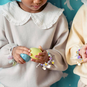 Children wearing colorful charm bracelets made with a kids bracelet-making kit playing with plastic eggs