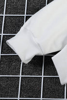 Close-up of white ribbed cuff on oversized graffiti rose hoodie sleeve on black grid background