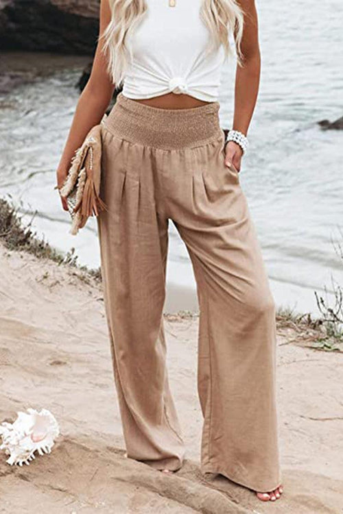 women wearing beige high-waist palazzo pants with white sleeveless top standing on beach