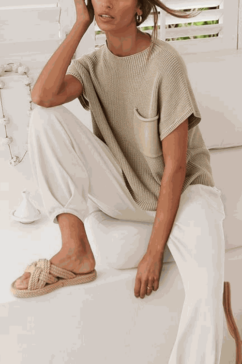 Woman wearing Comfy Couture Knit Sweater two-piece set with knit pullover and white pants sitting on couch