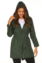 Woman wearing green outdoor and travel hooded raincoat windbreaker jacket with front zipper and pockets