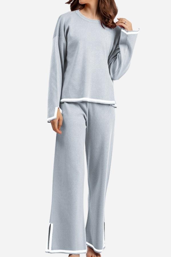 Woman wearing light gray long sleeved relaxed fit lounge two-piece set with white trim and wide-leg pants