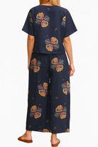 Back view of navy blue loose fit co-ord set with colorful floral prints, featuring a short-sleeve top and wide-leg trousers.