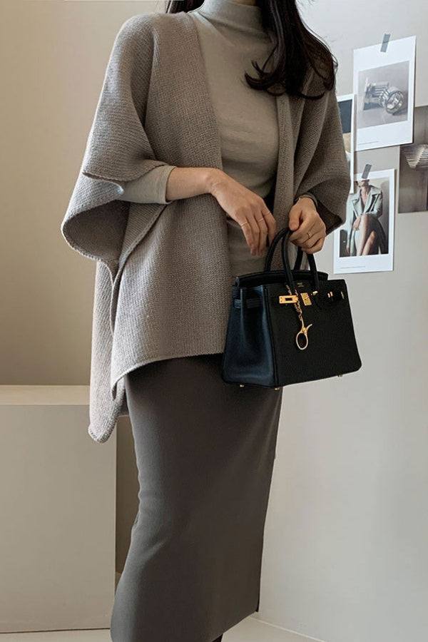 Woman wearing relaxed flowy open front knitwear cardigan in neutral tones holding black handbag