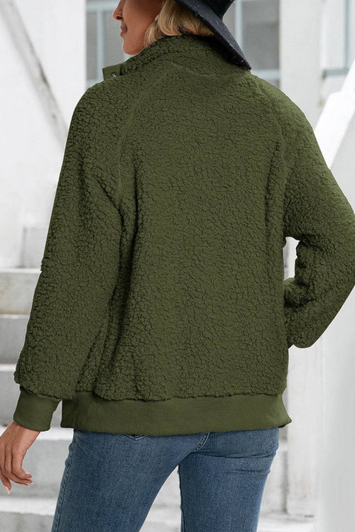 Woman wearing cozy long sleeve olive green sherpa jacket with fleece interior and button closure, styled casually with jeans and hat