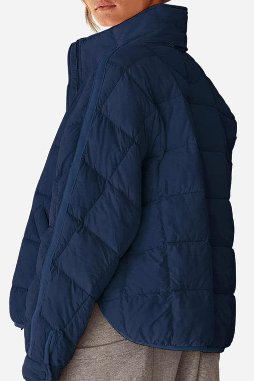 Navy lightweight puffer travel jacket with quilted pattern and high collar shown on model.