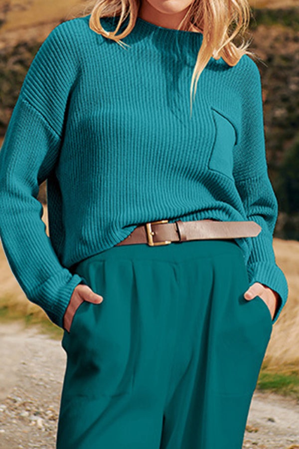 Woman wearing peacock blue relaxed knit sweater top and high-waisted trousers illustrating European minimalism style