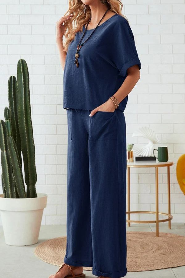 Woman wearing navy rolled cuff top and patch pocket pants set in relaxed fit living room setting