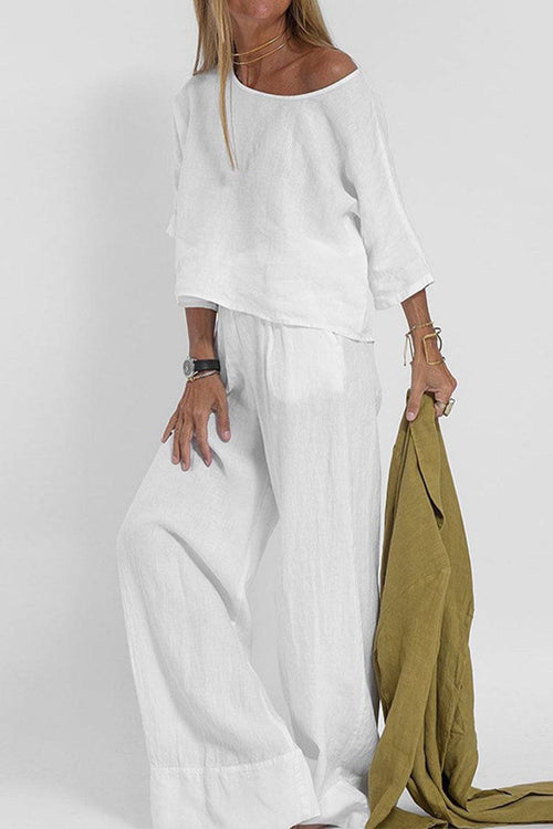 Woman wearing white short-sleeved pullover and wide trouser matching set holding mustard yellow jacket
