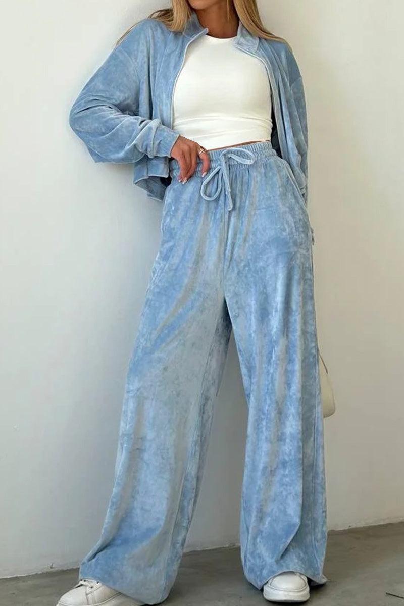 Woman wearing light blue velour zip up jacket and wide leg pants leisure two-piece co-ord with white crop top and sneakers