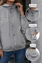 Light grey outdoor hooded raincoat with adjustable hood, button buckles, elastic cuffs, and pockets for weather protection.