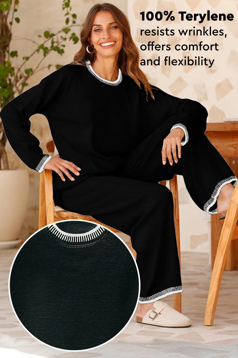 Woman wearing Chic Contrast Stitch black travel set with white stitching, made of wrinkle-resistant 100% terylene fabric, sitting on chair.
