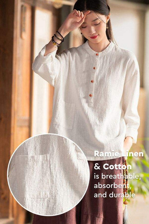Woman wearing breathable white ramie linen and cotton blouse with front buttons and long sleeves, standing indoors near window light