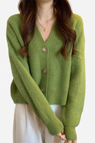 Green casual loose boxy cardigan with V-neck and buttons worn over white pants