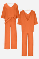 Elegant orange two-piece pantsuit with V-neck top and wide-leg pants, made from comfortable polyester fabric.