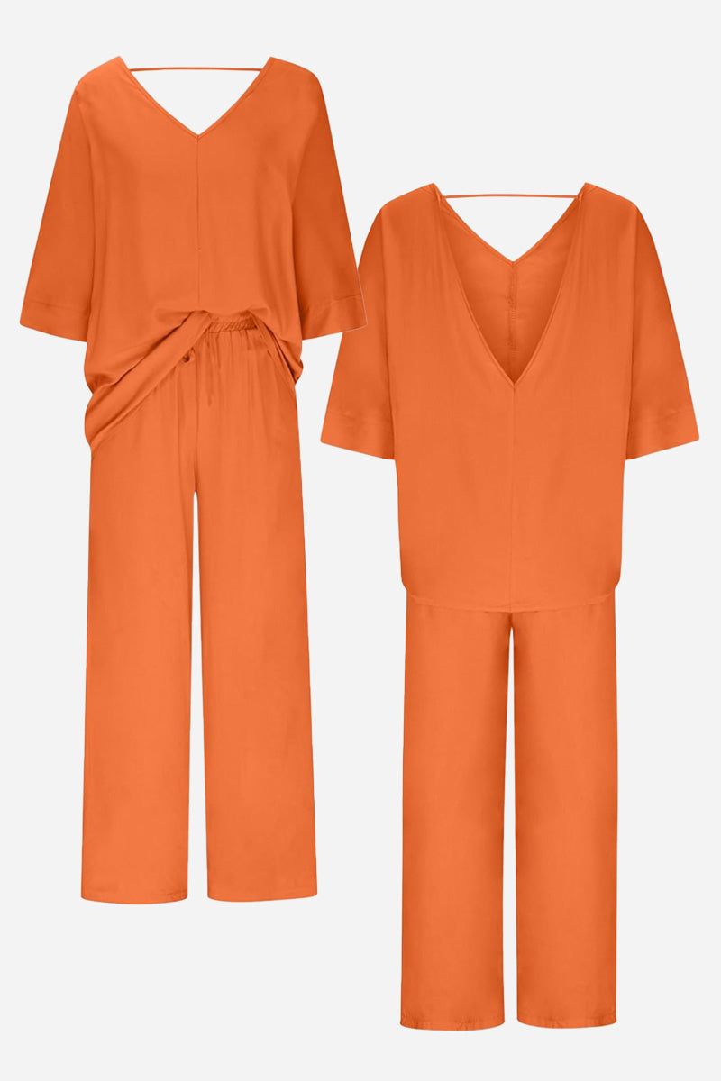 Elegant orange two-piece pantsuit with V-neck top and wide-leg pants, made from comfortable polyester fabric.