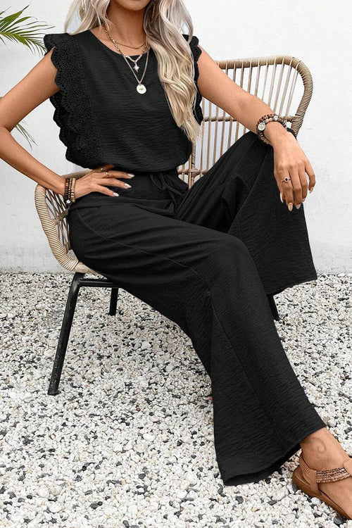 Woman wearing elegant black two-piece set with lace detail sitting on wicker chair outdoors