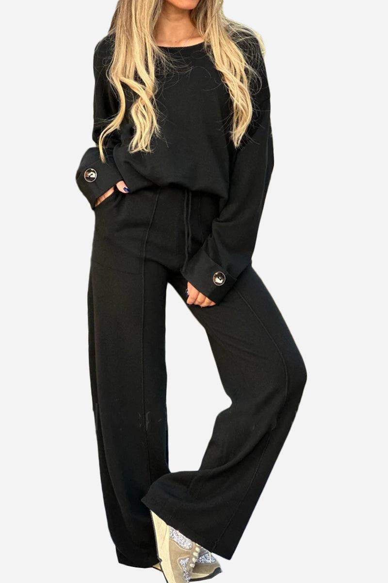 Black relaxed fit two-piece set with wide-leg pants and long sleeve top with button cuffs, ideal for comfortable travel and versatile styling.