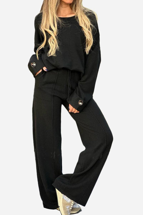 Black relaxed fit two-piece set with wide-leg pants and long sleeve top with button cuffs, ideal for comfortable travel and versatile styling.