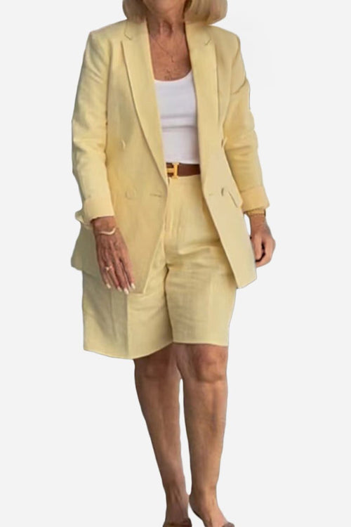Woman wearing stylish blazer and shorts two-piece set in light yellow with white top and belt.