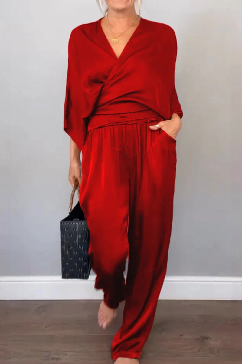 Woman wearing red Satin Wrap Lounge two-piece set with V-neck top and relaxed pants holding black handbag