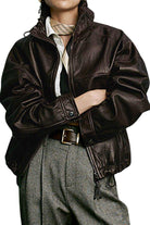 Woman wearing a glossy black genuine sheepskin leather jacket with structured shoulders and adjustable waist.