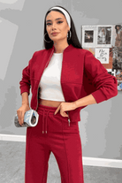 Woman wearing The Voyager Zip Set in red, featuring a zip-front sweatshirt and wide-leg joggers with pockets, styled with a white crop top and headband.