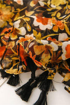 Twilight Blooms Scarf with warm floral print and black tassel edges, lightweight polyester fabric