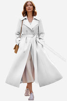 Woman wearing timeless retro belted trench coat with double-breasted design and wide lapels, styled with casual sneakers and brown shoulder bag