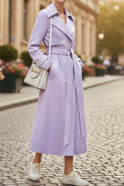 Woman wearing lavender timeless retro belted trench coat with double-breasted buttons and wide lapels walking outdoors