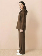 woman wearing brown lyocell-blend hooded set with wide-leg pants and hooded top against beige background