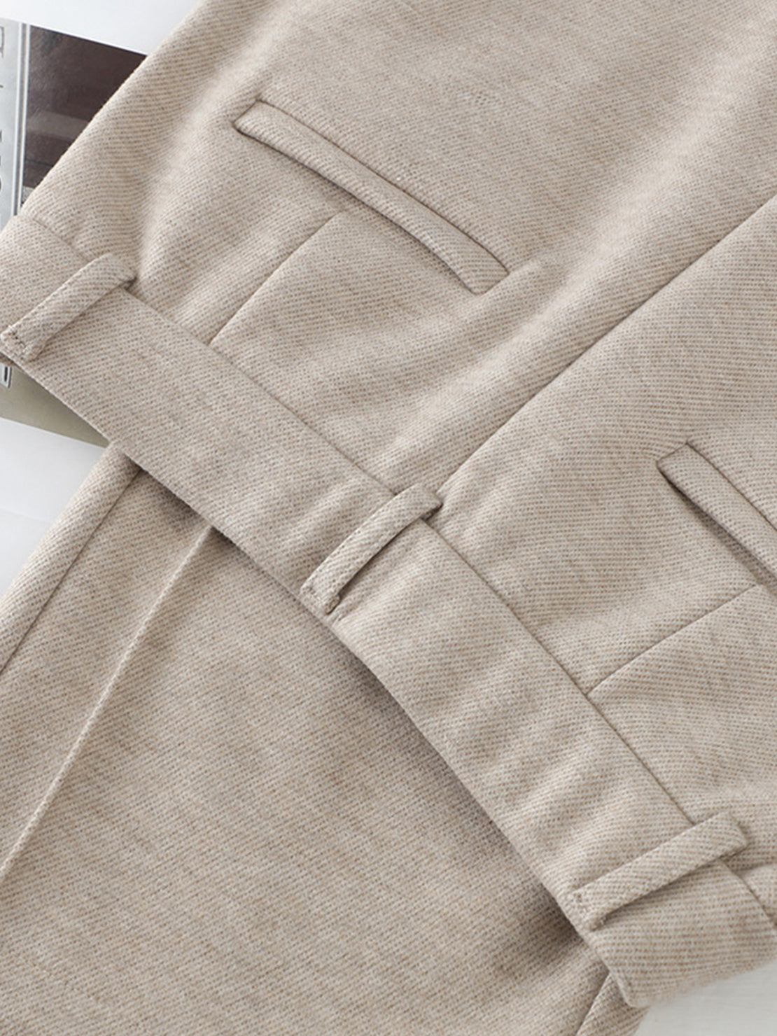Close-up of beige thermal wool blend trousers with elastic back waist and tailored pockets.