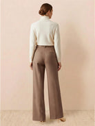 Woman wearing brown thermal wool blend trousers with wide-leg cut and elastic back waist, paired with a white turtleneck sweater.