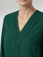 Pleated V-neck long-sleeve blouse with diagonal pleated panel and button cuffs, relaxed fit for comfortable wear
