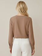 White pleated V-neck long-sleeve blouse with diagonal pleated panel and button cuffs