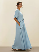 Woman wearing a knot-waist maxi dress with V-neckline and flowing skirt