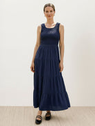Smocked sleeveless maxi dress with scoop neckline, tiered flowing skirt, and side pockets in lightweight fabric