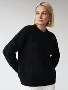 Oversized cable-knit crewneck sweater with dropped shoulders and diamond rope pattern.