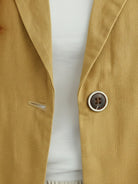 Cotton-linen blazer with notch lapels, two-button front, patch pockets, and natural textured fabric.