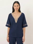 Mature woman wearing a lightweight linen top with V-neck and button details in a relaxed boxy shape