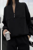 woman wearing a cotton-blended two-piece tracksuit with high collar and zipper in monochrome style