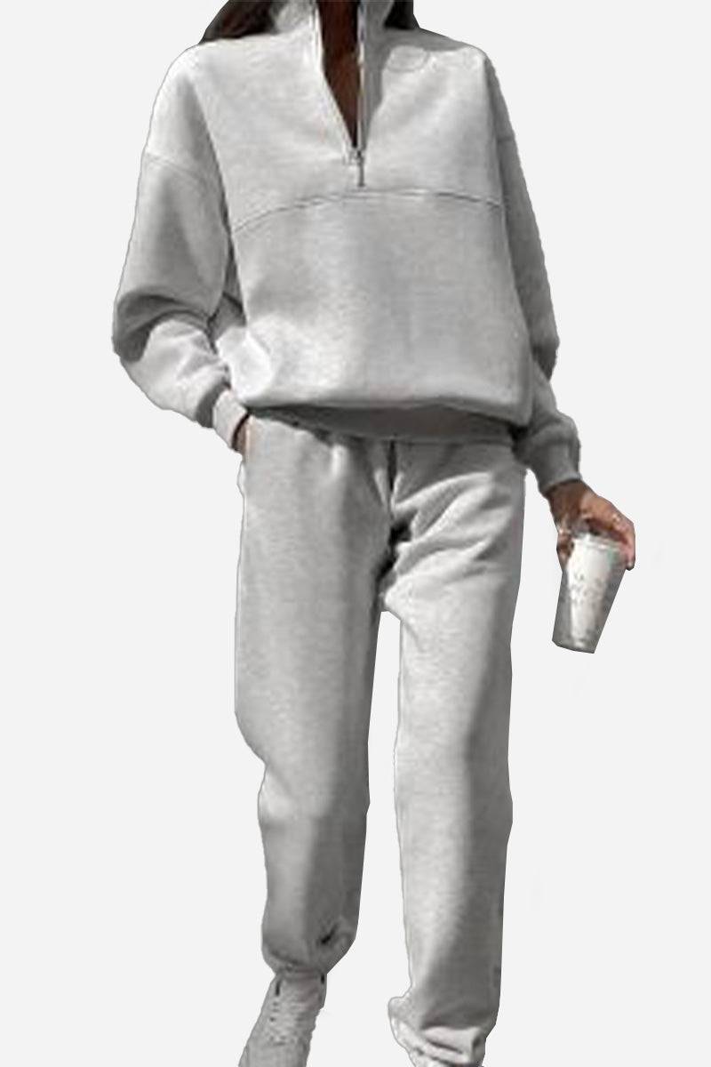 Woman wearing a soft cotton-blended two-piece tracksuit with a high collar and deep zipper in a monochrome relaxed silhouette