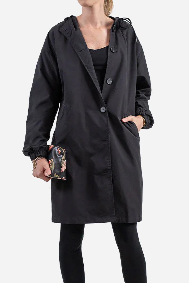 Woman wearing black water resistant oversized hooded windbreaker jacket with buttons and elastic cuffs