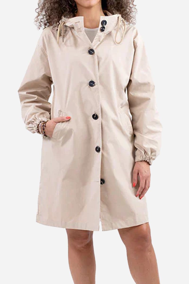 Woman wearing beige water resistant oversized hooded windbreaker rain jacket with button closure and pockets