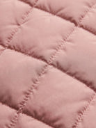 Close-up of pink quilted fabric on lightweight puffer travel jacket