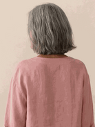 woman wearing pure linen age-defying button detail shirt sitting on wooden bench outdoors