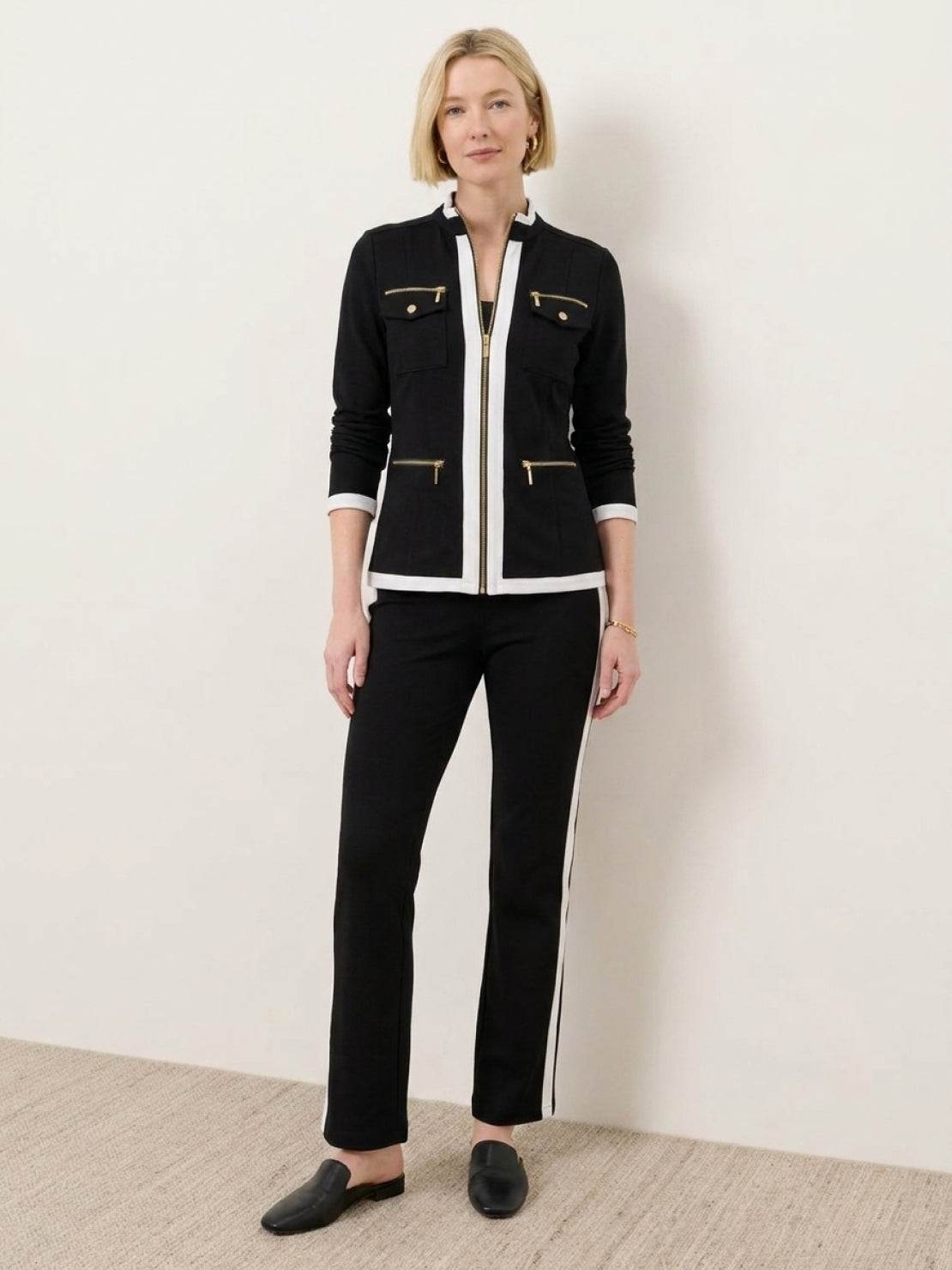Woman wearing sleek contrast zip two-piece outfit standing against white background