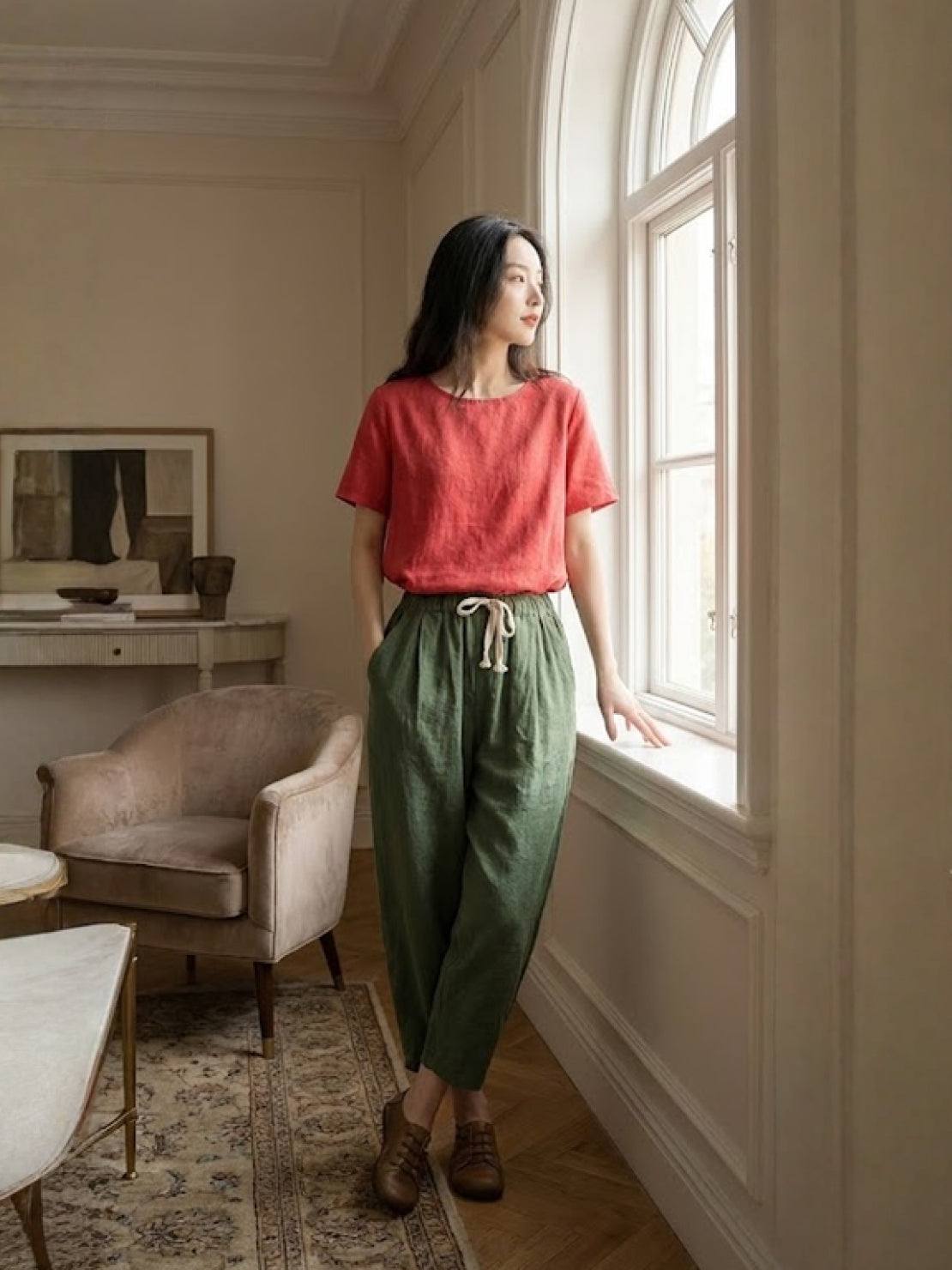 Woman wearing breezy relaxed fit straight pants sitting casually against a wall