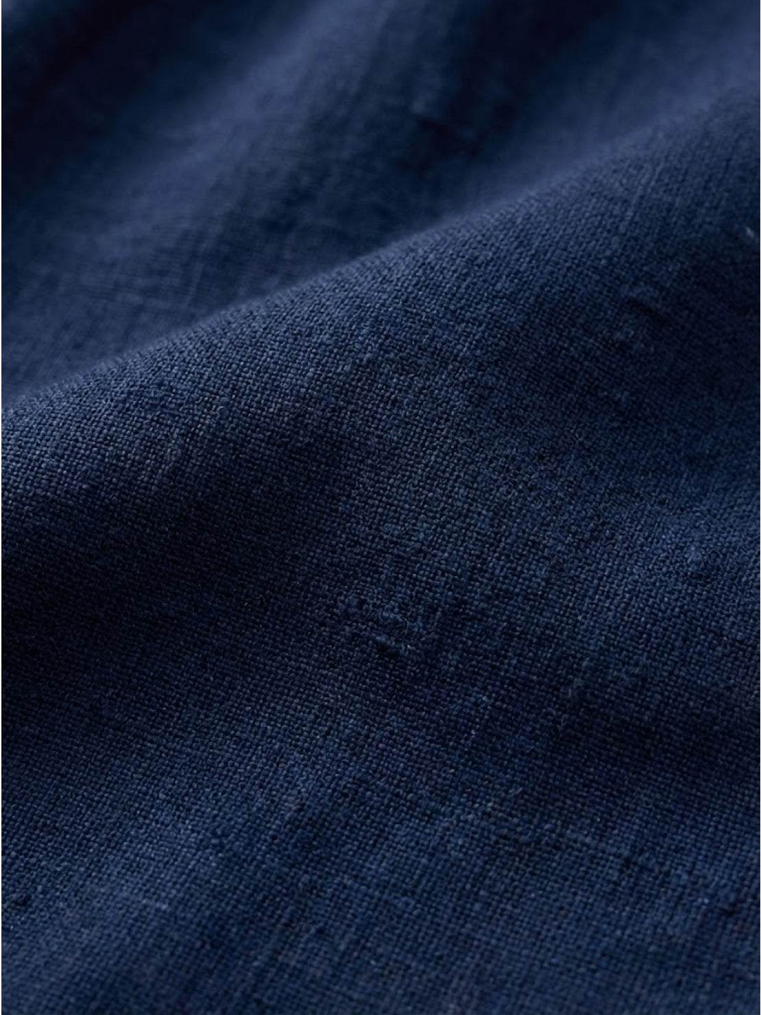 Woman wearing a capped-sleeve voluminous pleated midi dress with pockets and a flowing, stomach-flattening drape